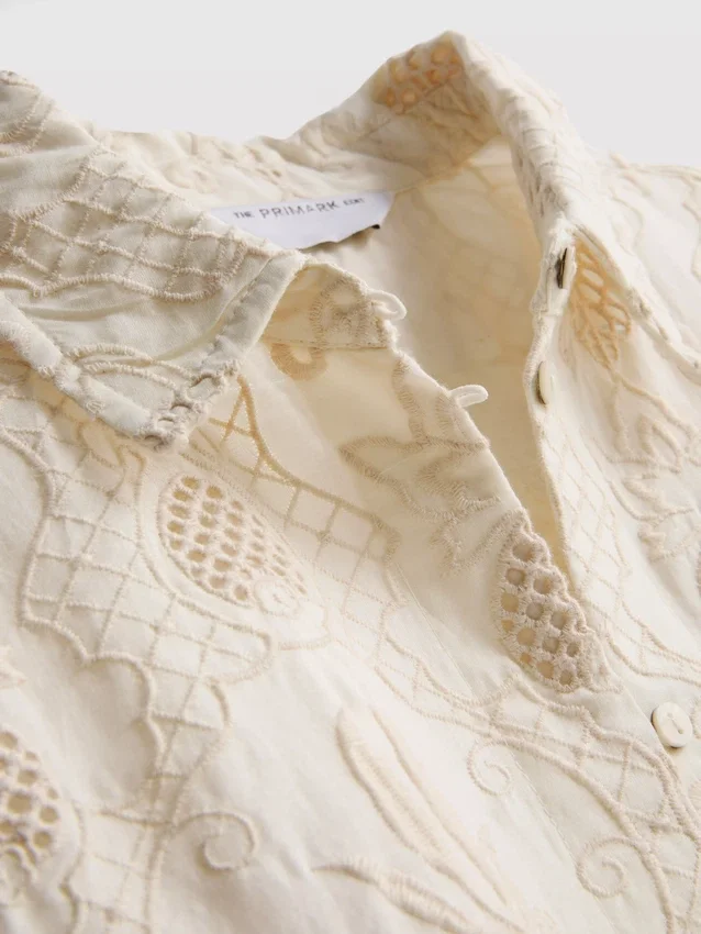The Edit -kauluspaita, jossa kaareva helma ja broderie-koristeet